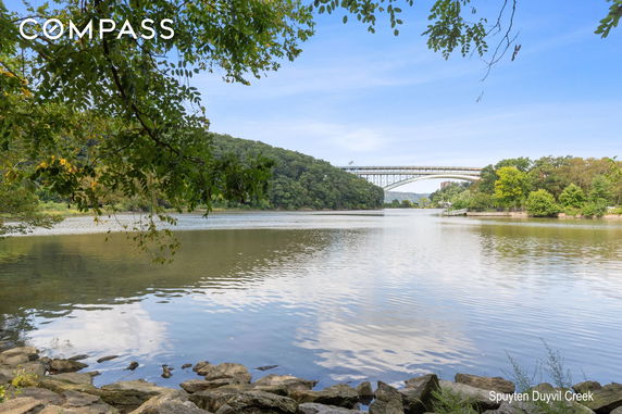 View of a creek with a bridge in the background surrounded by trees.
