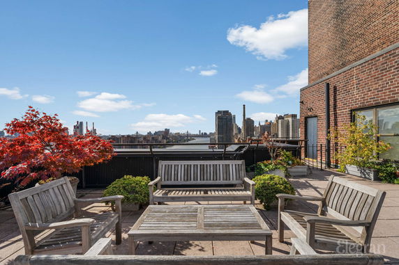 Rooftop with wooden seating and views of a cityscape.