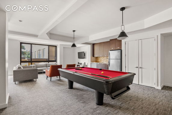 Room with billiards table and seating area next to a kitchenette.