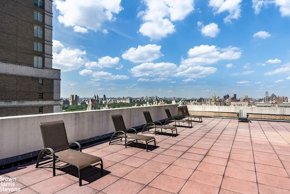 Rooftop area with multiple lounge chairs and surrounding city skyline.
