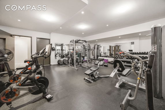 Interior view of a gym with exercise equipment and mirrors on the walls.