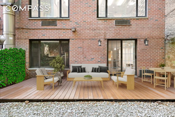 View of a building's back facade with a wooden deck and outdoor seating area.