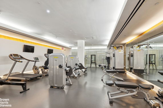 Interior view of a modern gym with exercise equipment and mirrored walls.