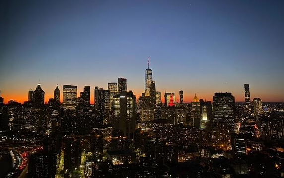 Panoramic view of a city skyline at sunset with illuminated skyscrapers.