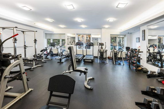 Interior view of a gym with various exercise equipment including treadmills, weight machines, and free weights.