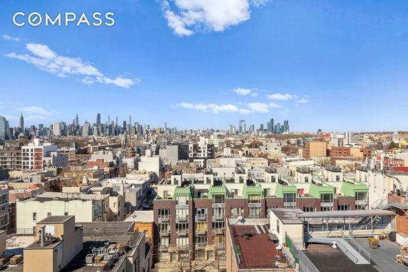 Panoramic view of a cityscape with numerous buildings and a distant skyline under a blue sky.