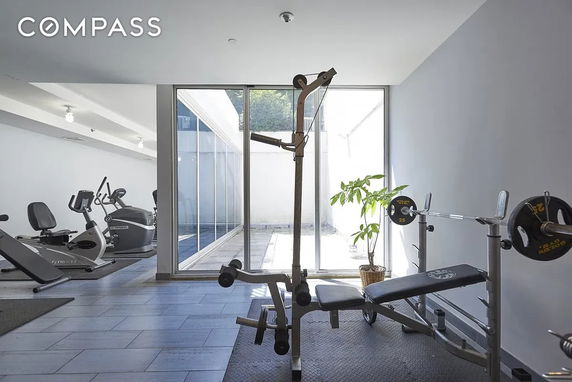 Indoor gym area with exercise equipment and large windows.