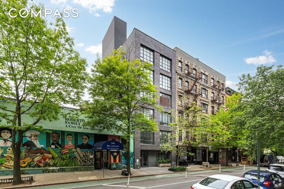 Front view of a multi-story building with large windows and adjacent colorful mural.