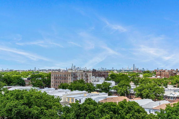Wide angle view of a cityscape with multiple buildings and greenery under a blue sky.