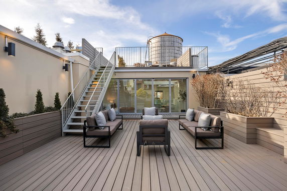 Rooftop terrace with metal staircase, seating area, and a water tank.