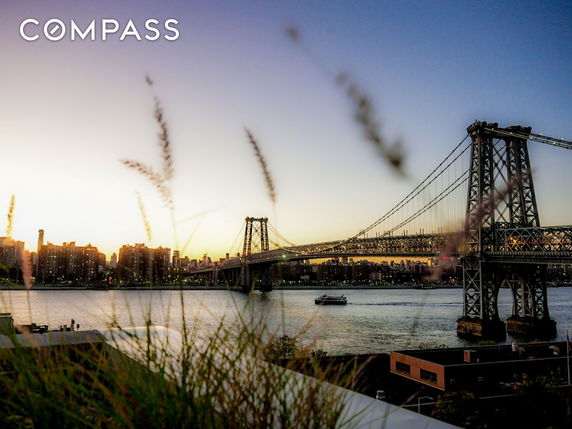 Panoramic view of a city skyline and a bridge over a river during sunset.