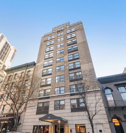 Front view of a multi-story apartment building with large windows.
