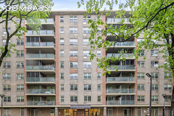Front view of a multi-story residential building with balconies and a canopy entrance.