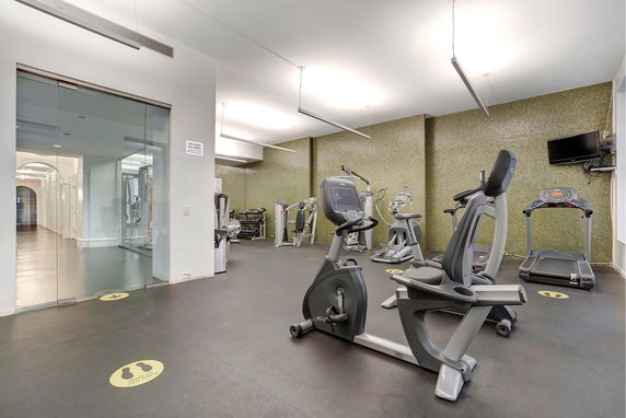 Interior view of a gym with exercise equipment including a treadmill and stationary bikes.