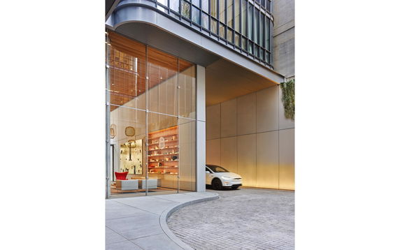 Covered parking area of a modern building with glass walls and a visible car.