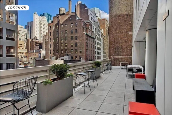 Rooftop terrace with seating and planters overlooking city buildings.