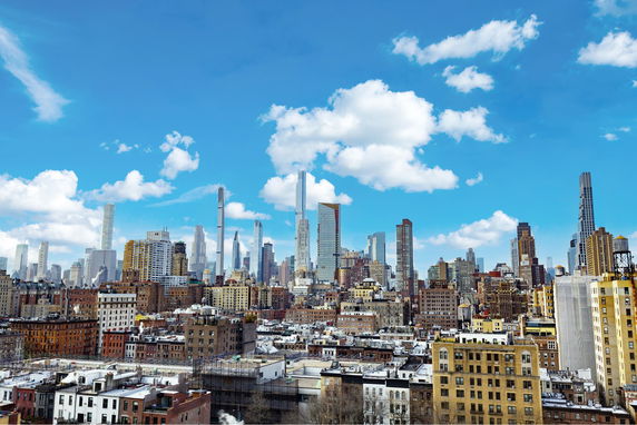 Panoramic cityscape view of tall skyscrapers under a blue sky with clouds.
