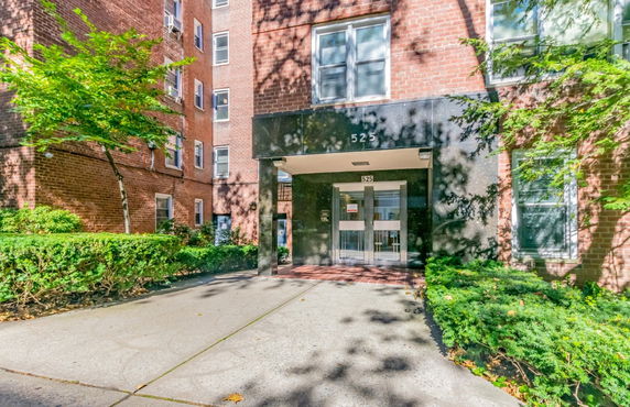 Front view of a brick multi-story apartment building with a glass entrance.