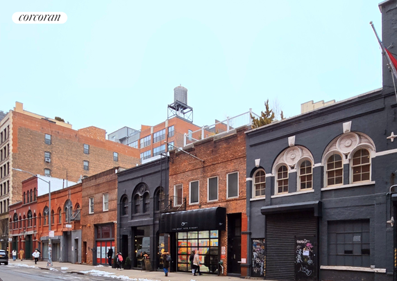 Front view of a row of brick buildings with various architectural features including arched windows.