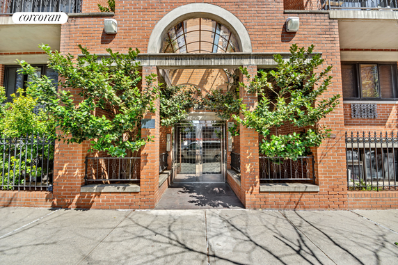 Front view of a multi-story brick building with a gated entrance.
