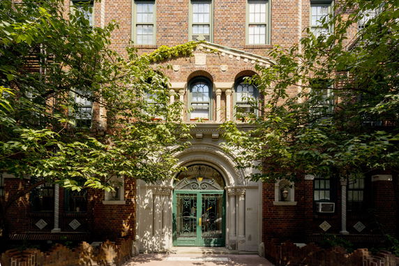 Front view of a brick building with arched entrance and decorative windows.