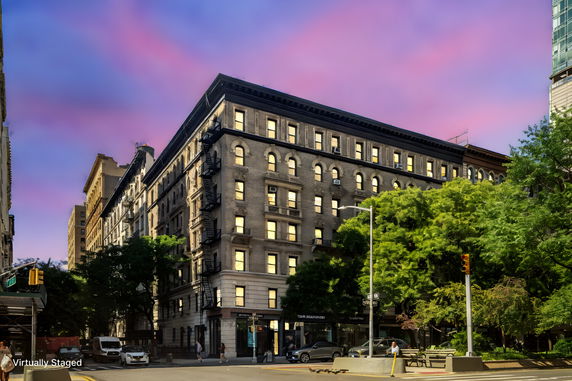 Front view of a multi-story building at an intersection with a vibrant sky background.