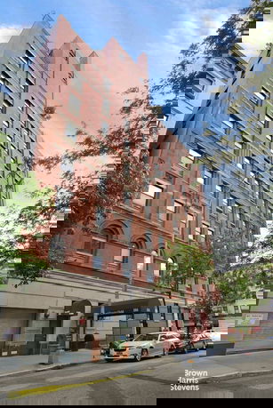 Front view of a multi-story brick building with large windows.