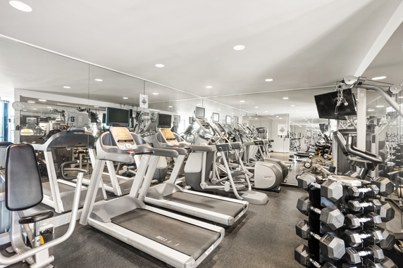 Interior view of a gym with exercise equipment including treadmills and weight machines.