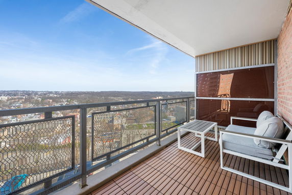 Balcony view overlooking a wide expanse with a railing and outdoor seating.