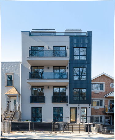 Front view of a modern multi-story building with balconies and large windows.