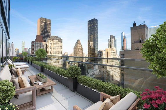 Rooftop terrace with seating and plants overlooking city skyline.