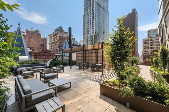 Rooftop area with seating and pergola, with surrounding city buildings visible.