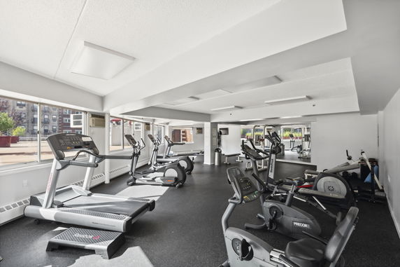 Indoor gym area with exercise equipment and large windows.