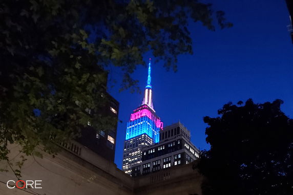 View of a building's colorful lights at night from a nearby location.