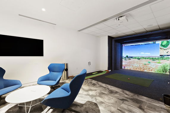 Indoor recreation area with a golf simulator and seating.