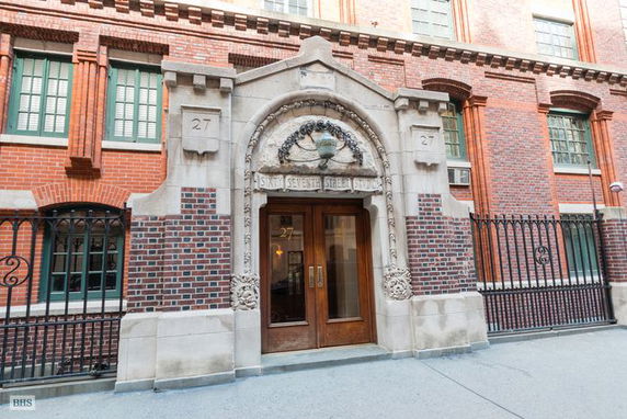 Front view of a brick building with ornate stone entrance and wooden doors.