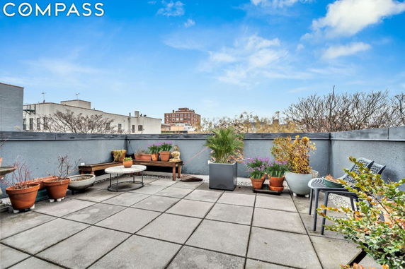 Rooftop patio with potted plants and seating area.
