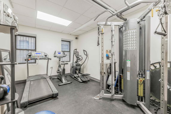 Room equipped with gym equipment including a treadmill, exercise bike, and multi-gym machine.