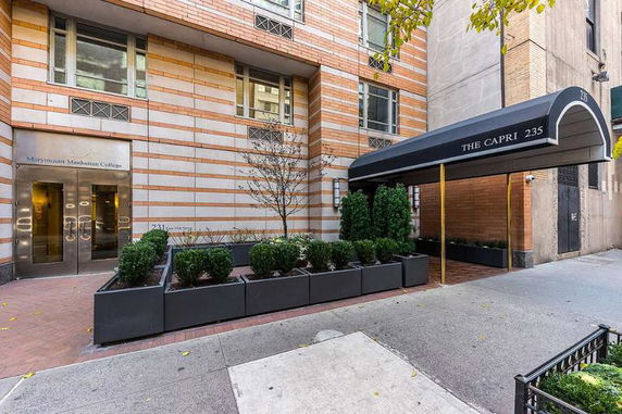 Front view of a building entrance with a canopy reading 'The Capri 235' and adjacent door marked 'Marymount Manhattan College.'