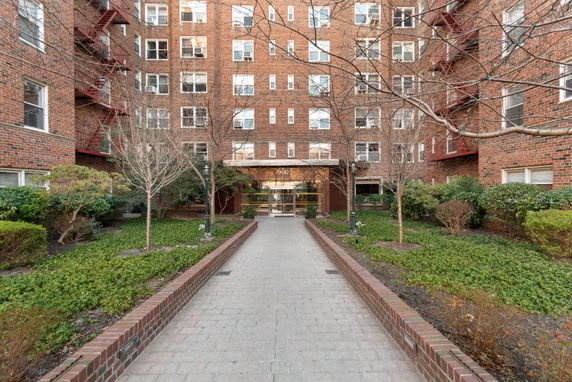 Front view of a multi-story brick apartment building with a central entrance.