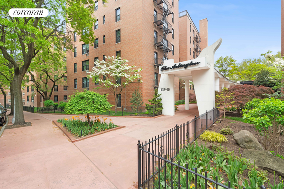 Front view of a multi-story brick apartment building with a white entrance structure.