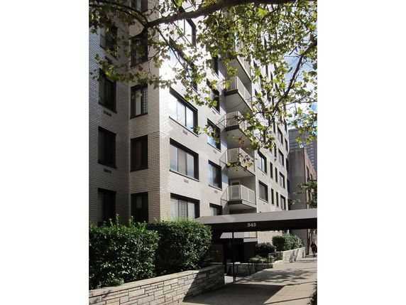 Front view of a multi-story apartment building with balconies and an entrance canopy.