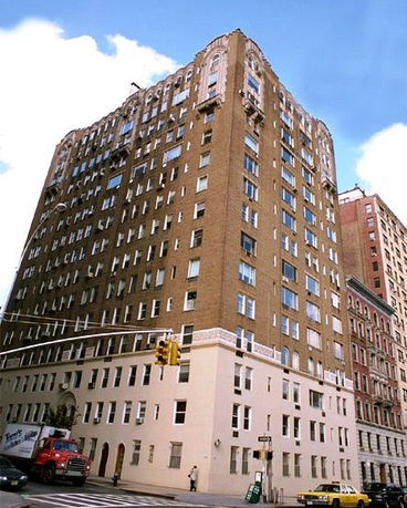 Front view of a large multi-story brick building on a city street corner.
