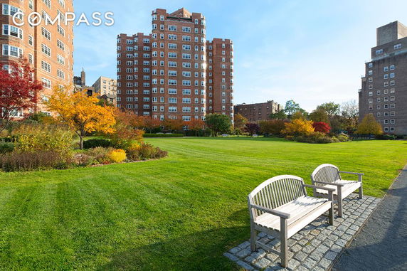 View of residential buildings with a well-maintained lawn and garden area.