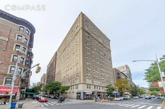 Front view of a tall, multi-story brick building on a street corner.