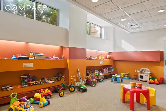 Indoor children's play area with toys and small furniture.