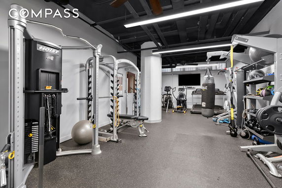 Indoor gym area with various exercise equipment, including treadmills, weight machines, and a punching bag.