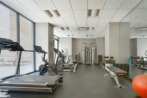 Indoor gym area with various exercise equipment including treadmills, stationary bikes, and weight machines.