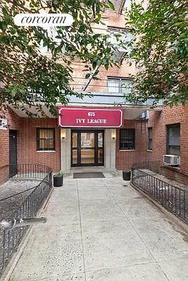 Front view of a brick apartment building with an entrance canopy reading 'Ivy League'.