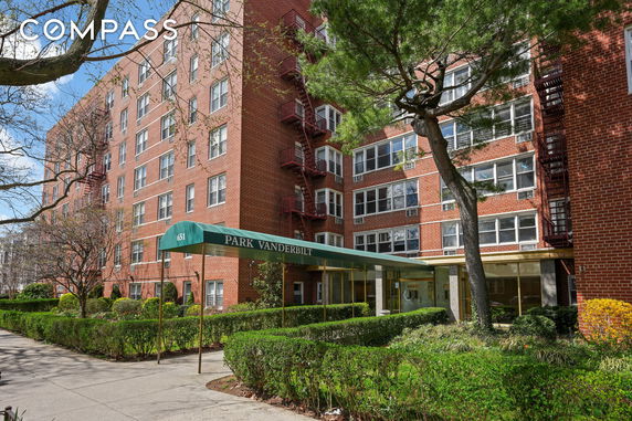 Front view of a multi-story brick apartment building with a green canopy entrance.